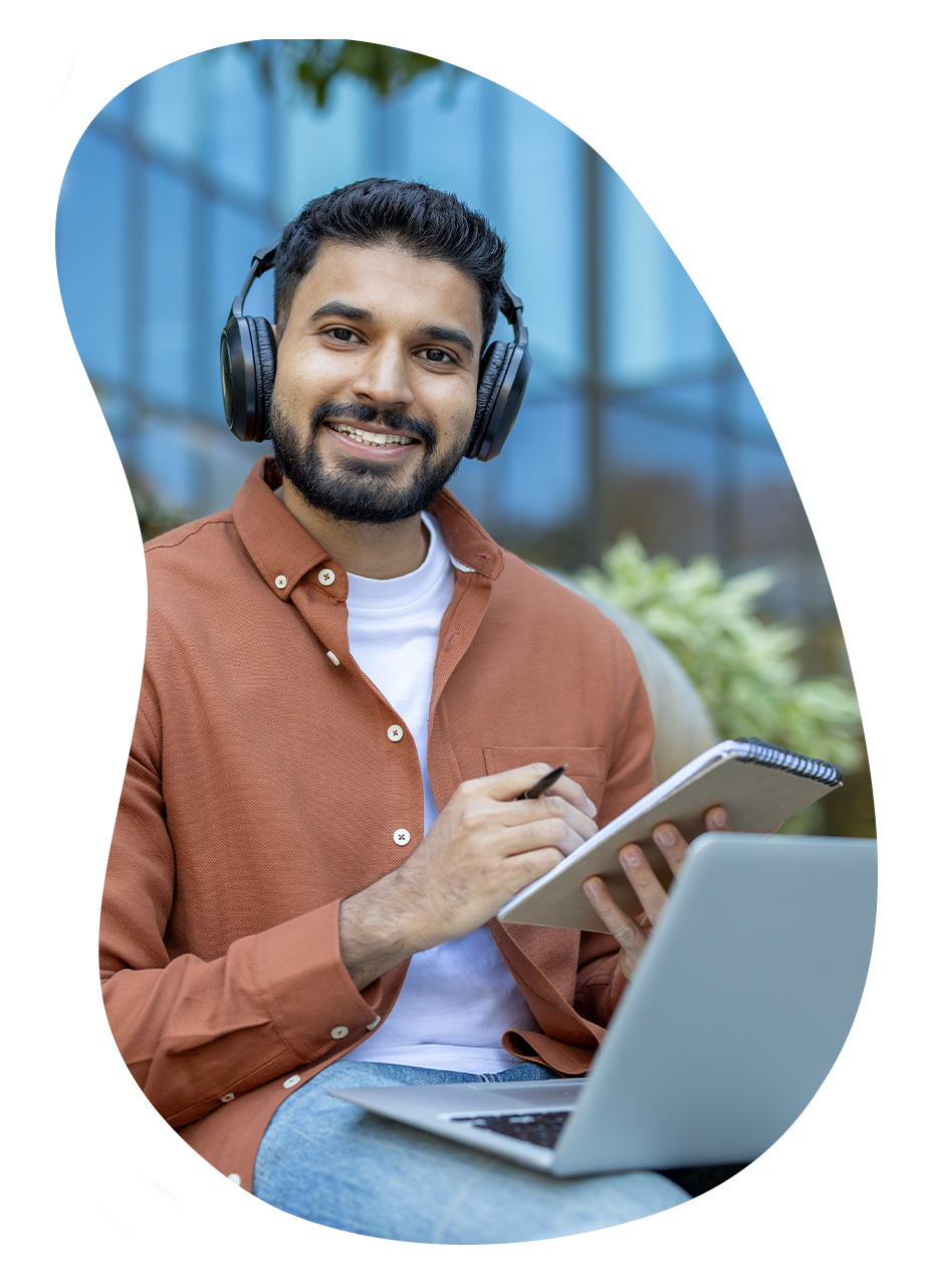 Homme étudiant en ligne avec un casque audio, prenant des notes sur un carnet devant son ordinateur portable, illustrant la formation e-learning asynchrone.